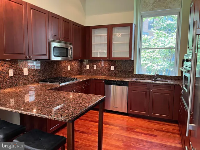 a kitchen with granite countertop wooden cabinets a stove top oven a sink and dishwasher