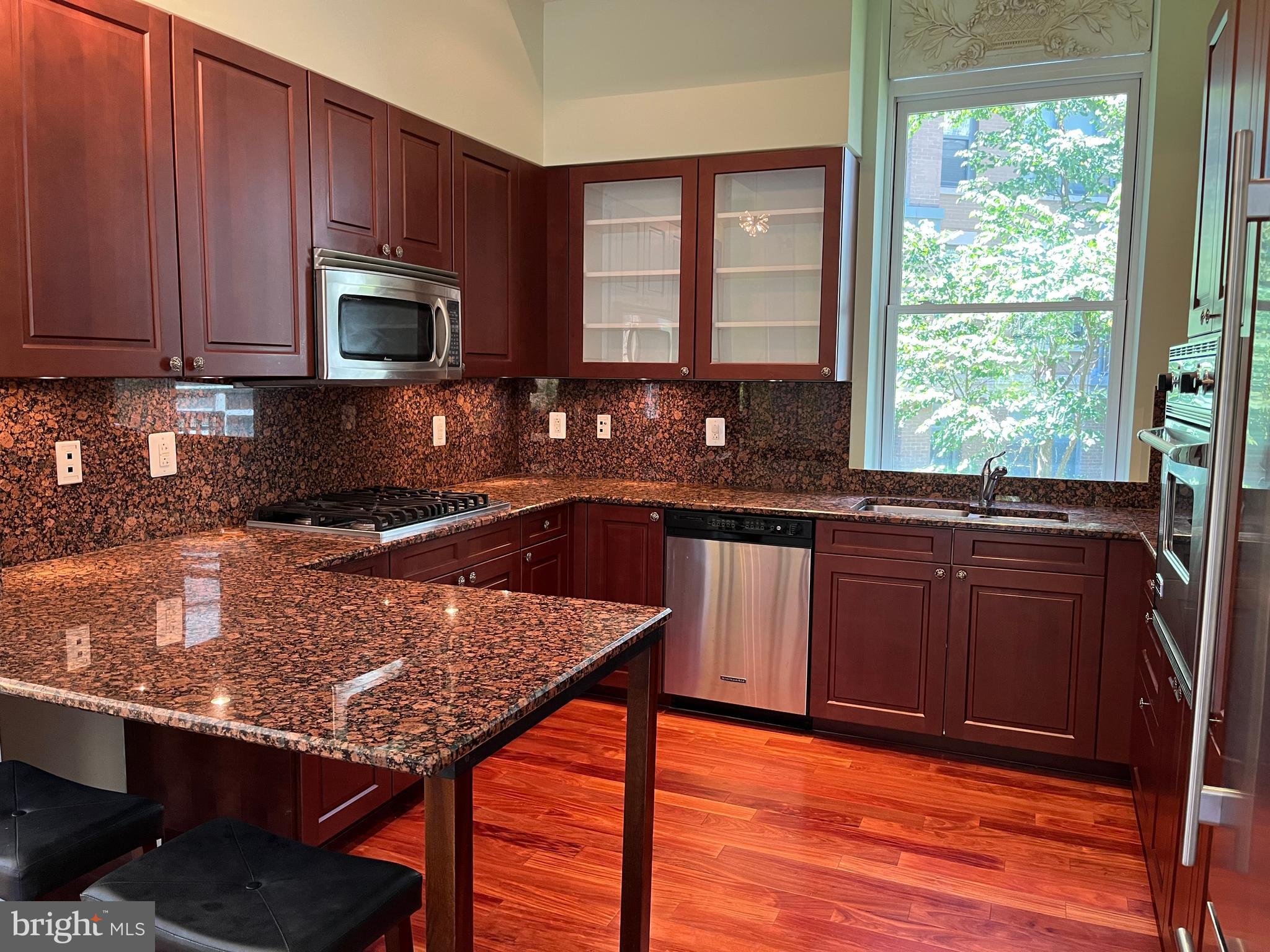 2425 L Street Northwest, Unit 215 Washington, DC 20037 - Photo 16 of 38 a kitchen with granite countertop wooden cabinets a stove top oven a sink and dishwasher