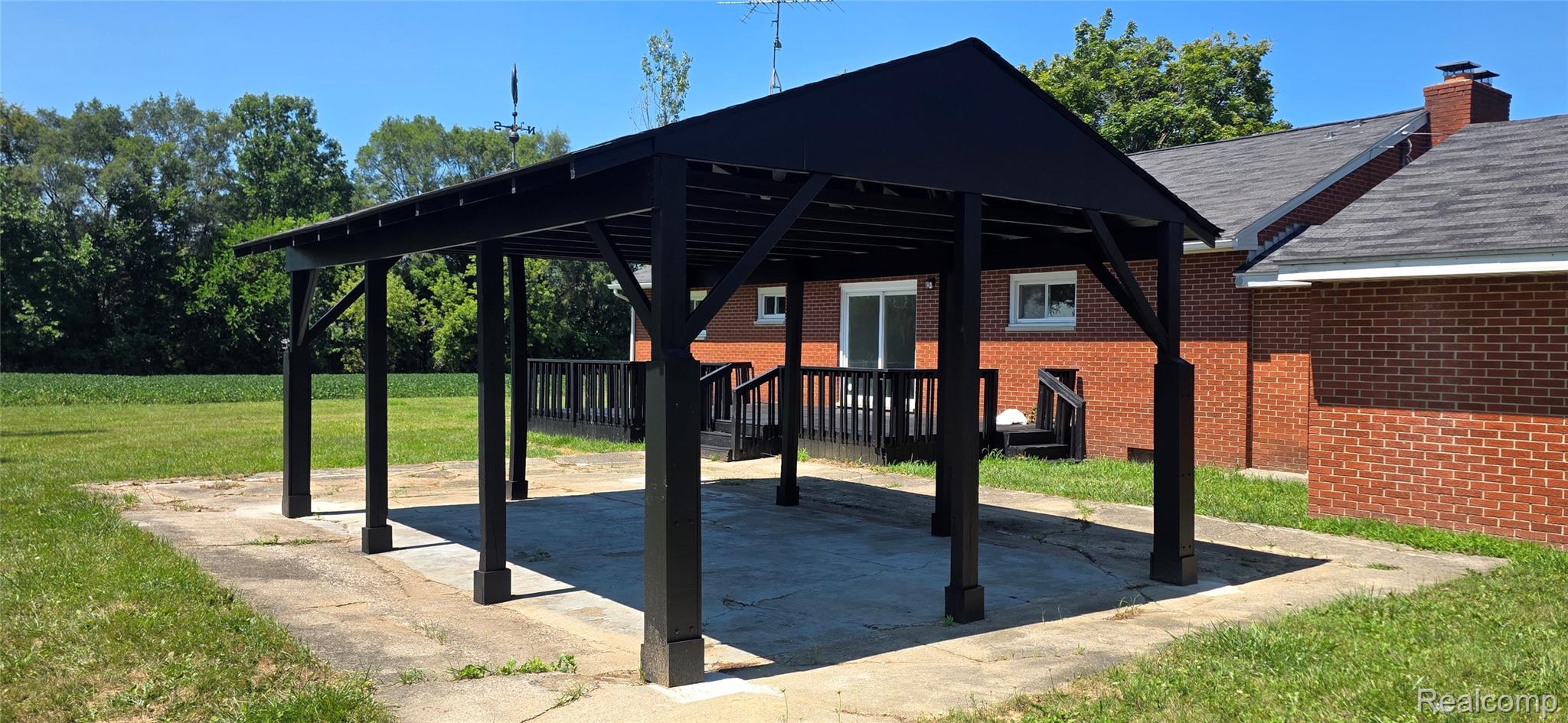 4363 West Dodge Road Clio, MI 48420 - Photo 15 of 52 Detached black pergola with a concrete pad, surrounded by a manicured lawn and mature trees