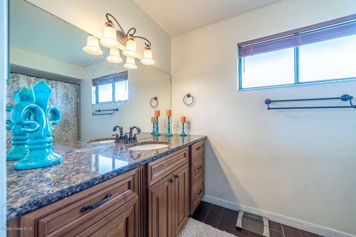 1508 Meadowbrook Road Northeast Palm Bay, FL 32905 - Photo 22 of 42 a bathroom with a granite countertop sink a mirror and a window