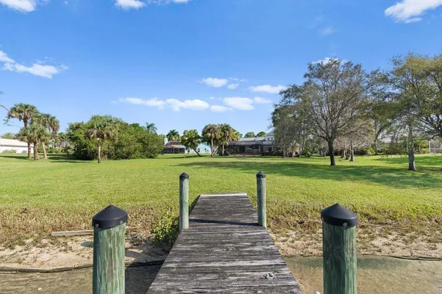 an aerial view of a house with a yard lake and trees all around