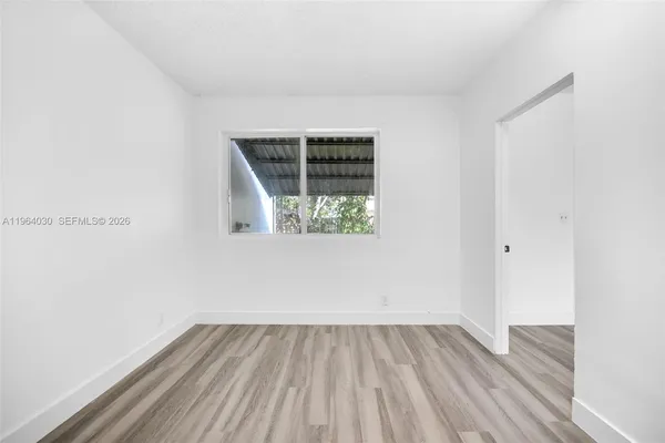 an empty room with wooden floor and window