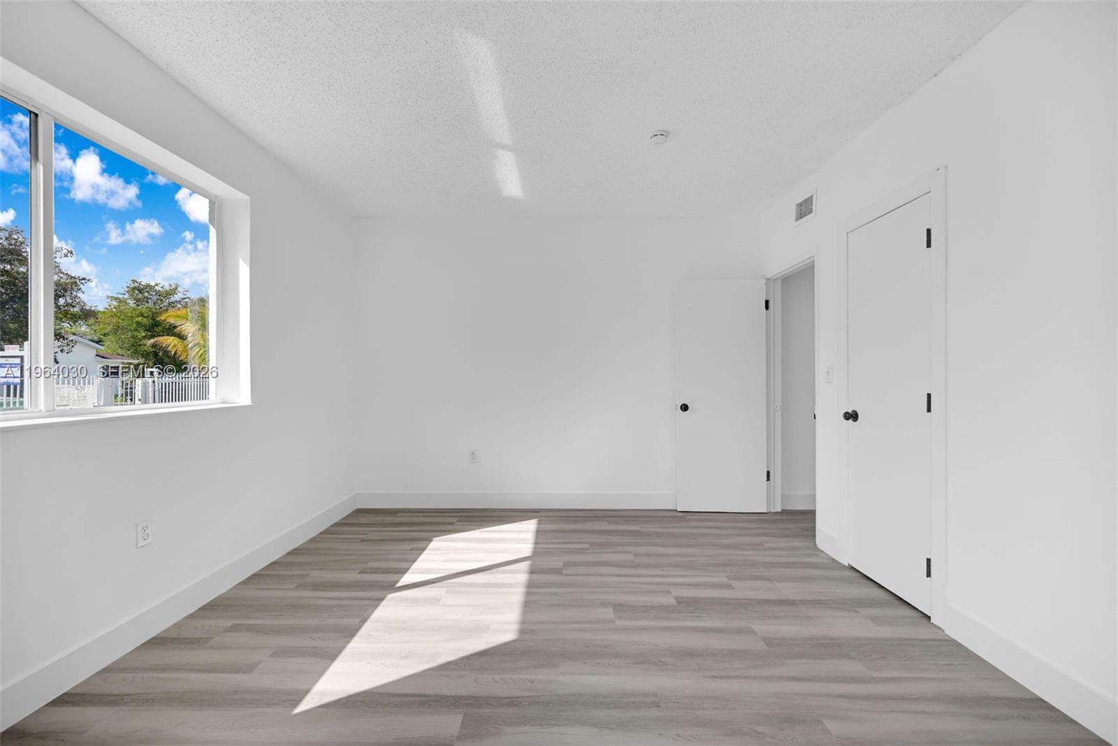 1391 Northwest 102nd Street, Unit 1391 Miami, FL 33147 - Photo 29 of 32 a view of an empty room with wooden floor and a window
