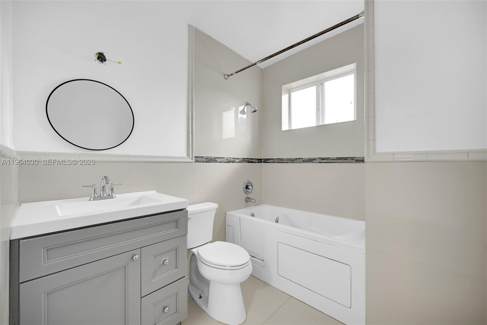 1391 Northwest 102nd Street, Unit 1391 Miami, FL 33147 - Photo 8 of 32 a bathroom with a toilet a sink a mirror and vanity
