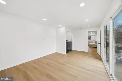 a view of an empty room with kitchen and a window