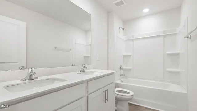 a bathroom with a double vanity sink toilet mirror and shower