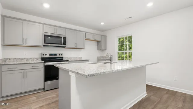 a kitchen with stainless steel appliances granite countertop a sink a stove a microwave and cabinets