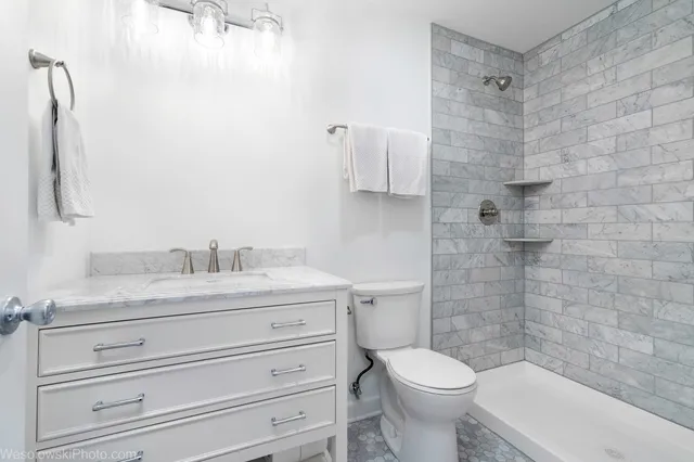 a bathroom with a granite countertop toilet sink and mirror