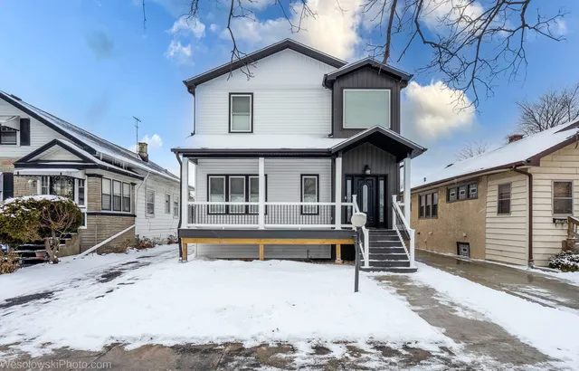 a front view of a house with a yard and a large tree