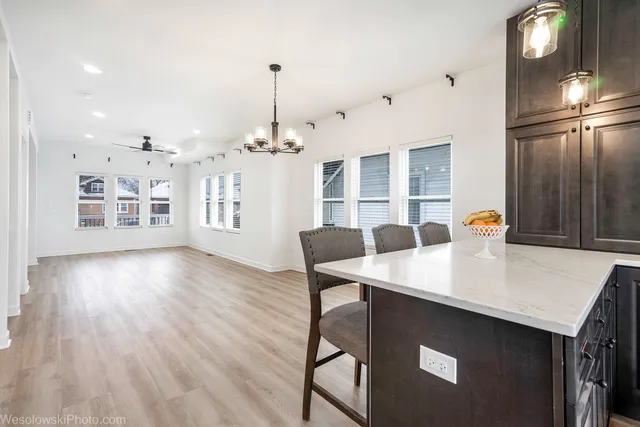 a kitchen with stainless steel appliances granite countertop a table chairs and a refrigerator