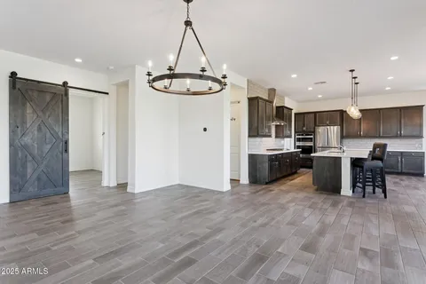 a kitchen with stainless steel appliances kitchen island granite countertop a table chairs and a refrigerator