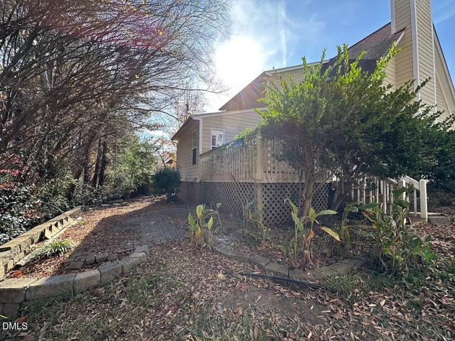 a view of a backyard with plants and large trees