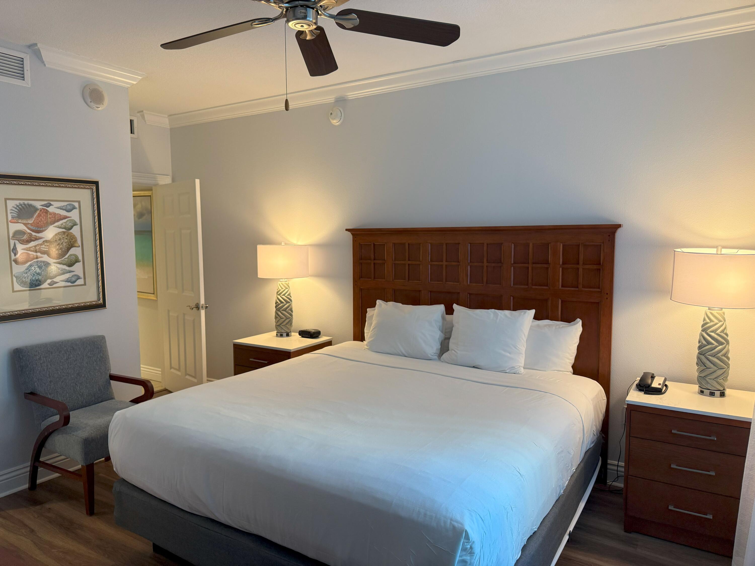 10 Harbor Boulevard, Unit E102F Destin, FL 32541 - Photo 15 of 29 a bedroom with a bed and a lamp on the dresser