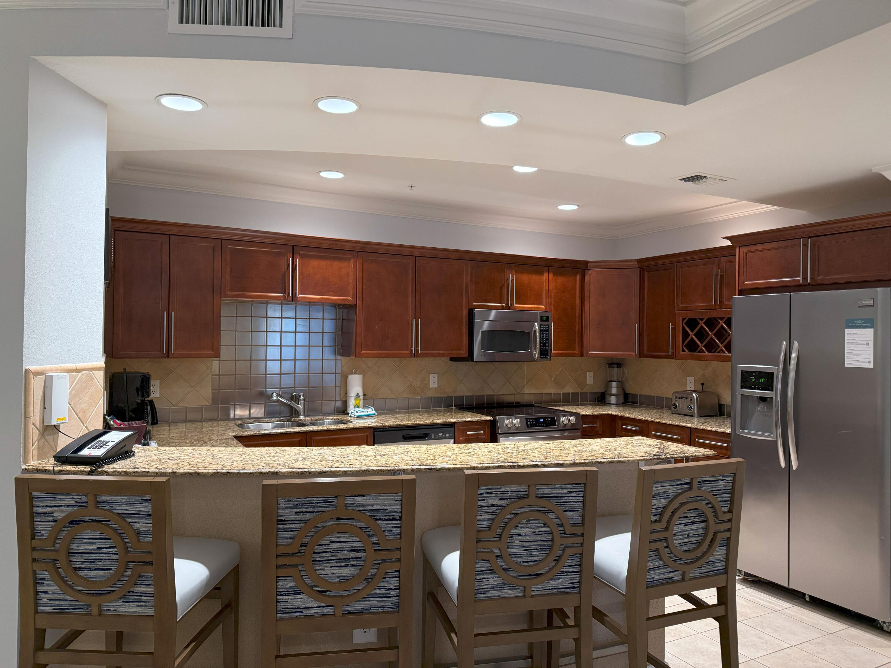 10 Harbor Boulevard, Unit E102F Destin, FL 32541 - Photo 8 of 29 a kitchen with stainless steel appliances granite countertop a sink a stove a refrigerator cabinets and chairs