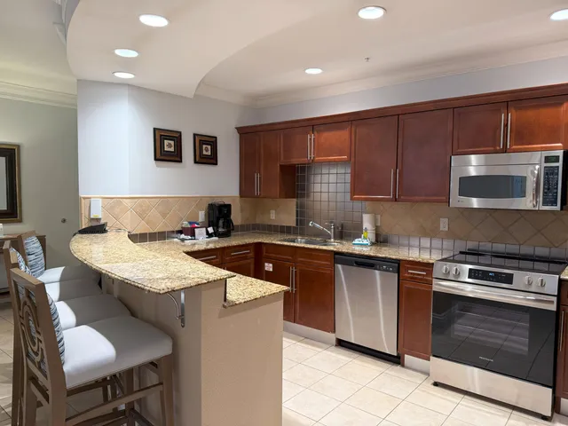 a kitchen with stainless steel appliances granite countertop a refrigerator stove top oven and sink