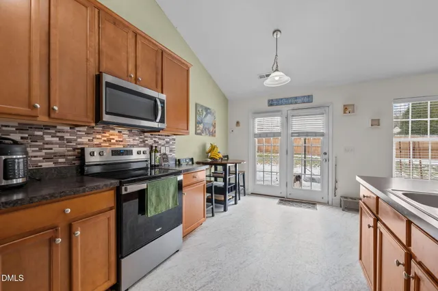 a kitchen with stainless steel appliances granite countertop a stove top oven a sink dishwasher a dining table and chairs with wooden floor