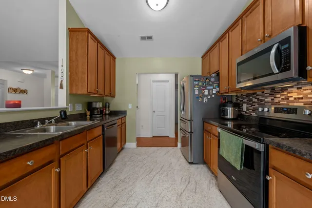 a kitchen with stainless steel appliances granite countertop a stove a sink and a microwave