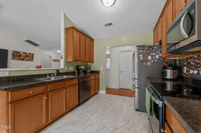 a kitchen with granite countertop a sink stove and refrigerator