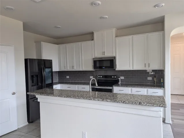 a kitchen with stainless steel appliances granite countertop a refrigerator a stove a sink and a granite counter tops