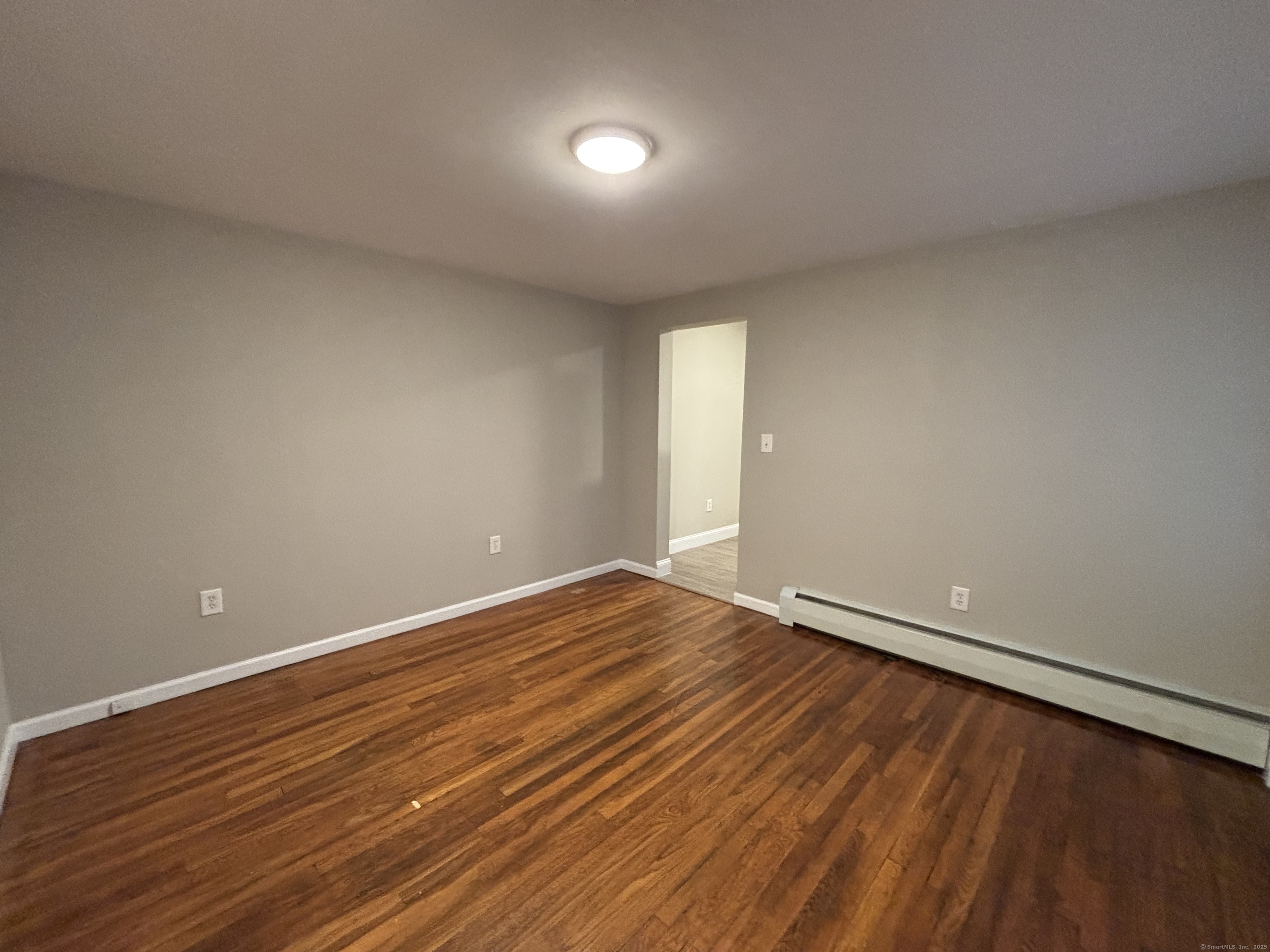 225 Golden Hill Street, Unit 3F Bridgeport, CT 06604 - Photo 5 of 12 a view of an empty room with wooden floor and a window