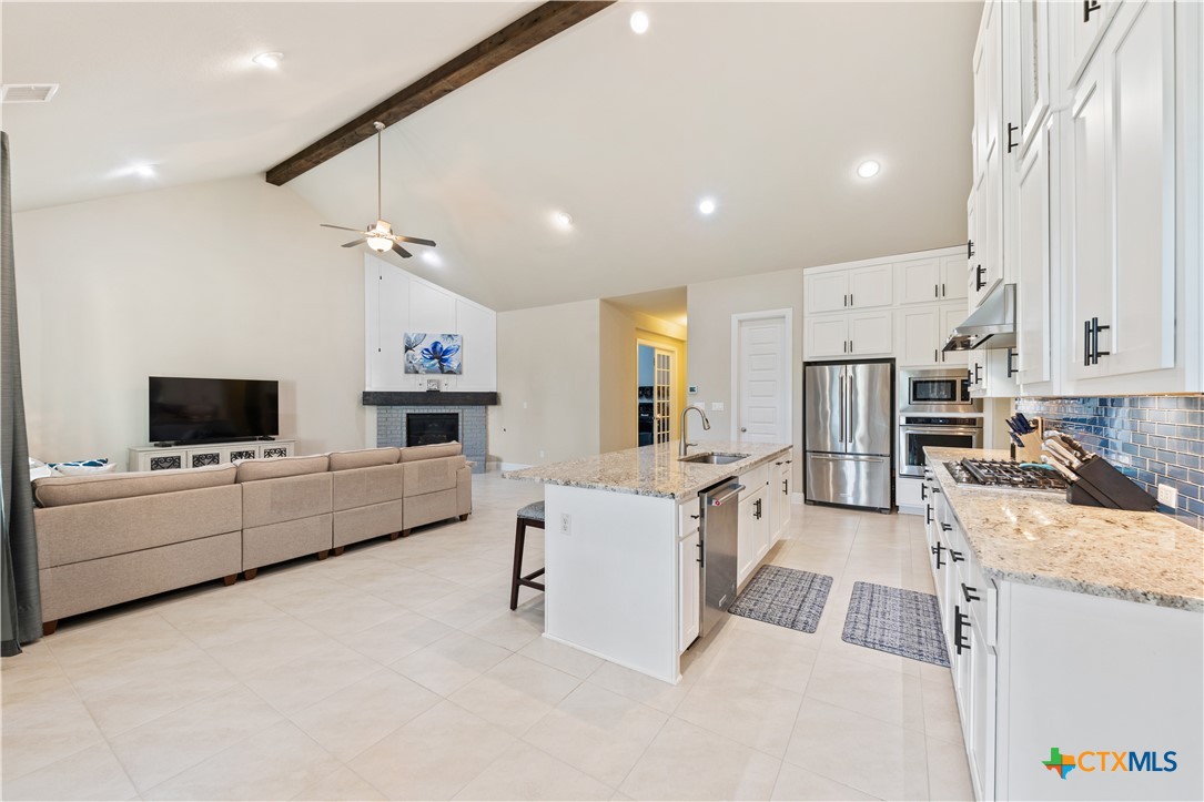 264 Axis Loop Georgetown, TX 78628 - Photo 13 of 33 a large white kitchen with stainless steel appliances granite countertop lots of white cabinets a stove and a couch
