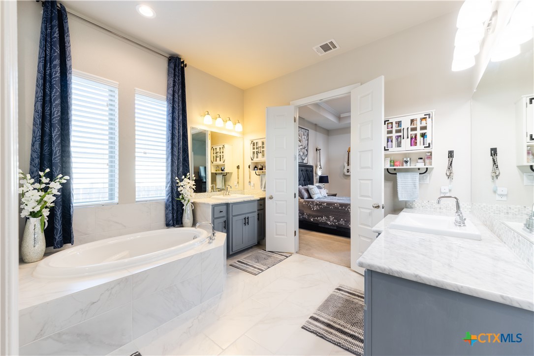 264 Axis Loop Georgetown, TX 78628 - Photo 19 of 33 a bathroom with a tub a sink and a large mirror