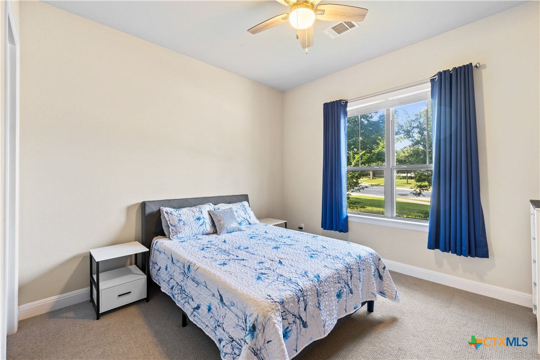 264 Axis Loop Georgetown, TX 78628 - Photo 21 of 33 a bedroom with a large bed and a chandelier