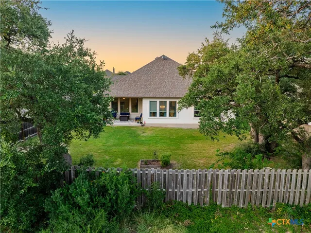 a view of a white house with a small yard and large tree