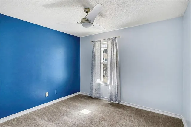 an empty room with windows and ceiling fan