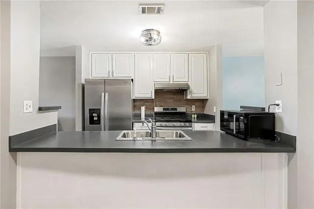 a kitchen with stainless steel appliances granite countertop a sink a stove and white cabinets