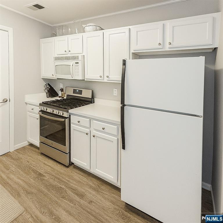 1052 Chedworth Circle Mahwah, NJ 07430 - Photo 6 of 16 a kitchen with a refrigerator a stove top oven and white cabinets