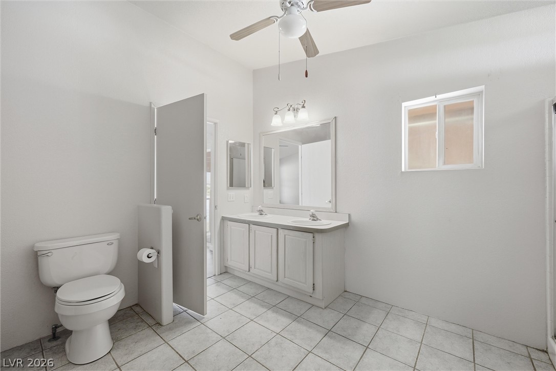 1531 West Harris Farm Road Pahrump, NV 89060 - Photo 26 of 37 A well-lit bathroom features a dual vanity, tiled flooring, and a ceiling fan for comfort.