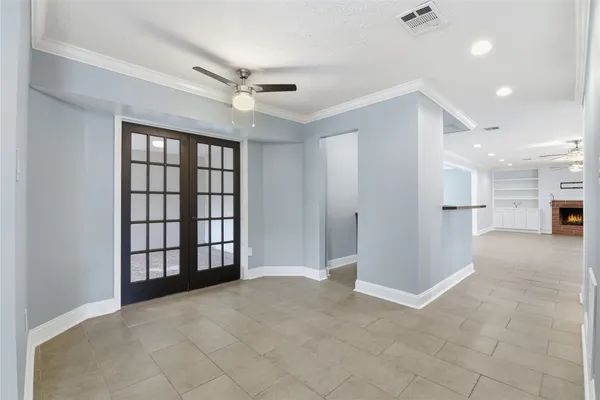 a view of an empty room with a cabinet and chandelier fan
