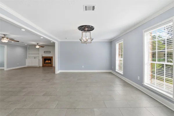 a view of an empty room with window and chandelier fan