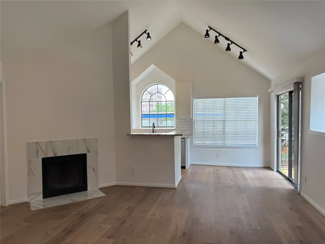 an empty room with wooden floor a fireplace and windows