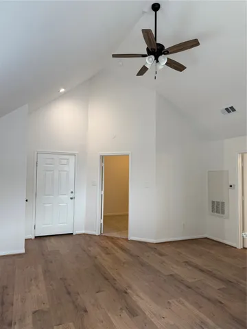 a view of a room with a wooden floor and a ceiling fan