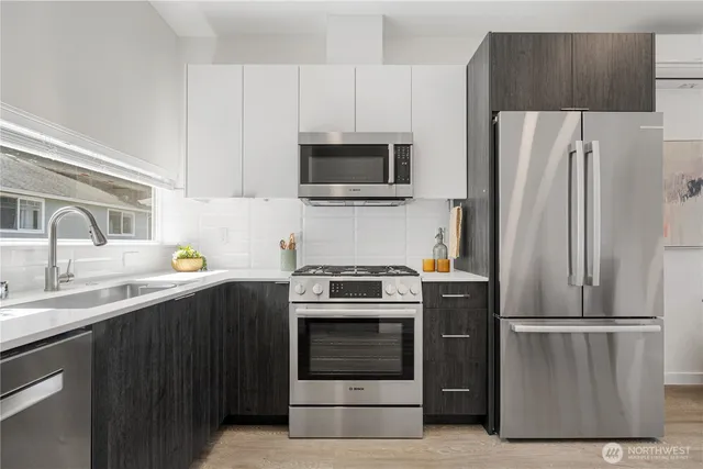 a kitchen with stainless steel appliances a stove a microwave and a sink