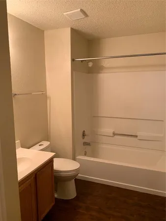a bathroom with a granite countertop bathtub shower sink vanity and toilet
