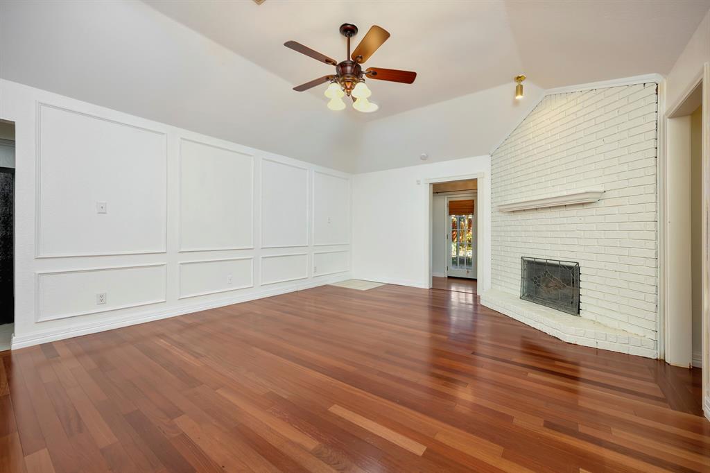 3409 Crescent Court Bedford, TX 76021 - Photo 8 of 40 an empty room with wooden floor a ceiling fan a fireplace and windows