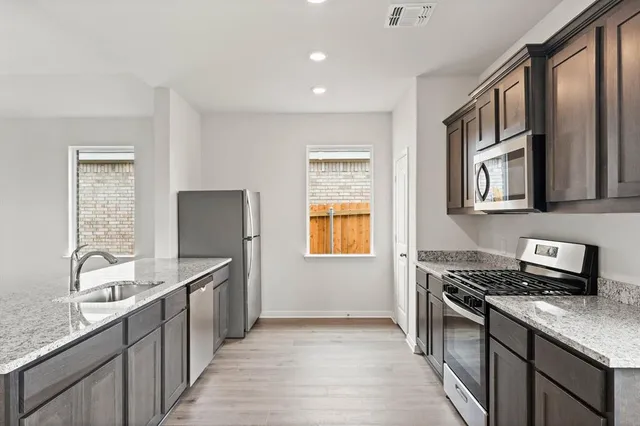 a kitchen with stainless steel appliances granite countertop a sink stove and refrigerator