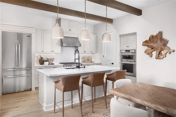 a kitchen with stainless steel appliances granite countertop a sink a stove a refrigerator and island with wooden floor
