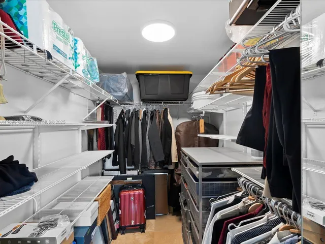 a view of walk in closet with clothes and shoes