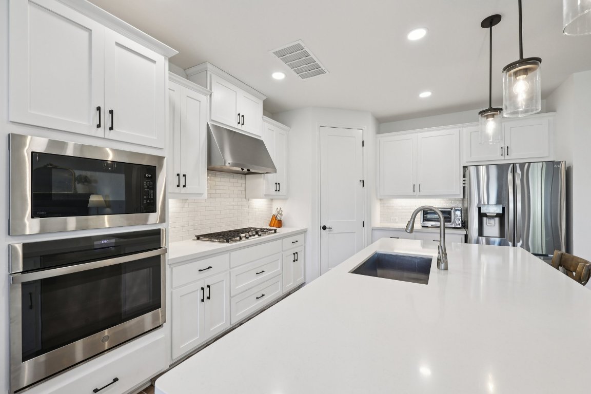 2913 Fallcrest Bend Leander, TX 78641 - Photo 14 of 40 a kitchen with stainless steel appliances kitchen island granite countertop a stove a sink and a refrigerator