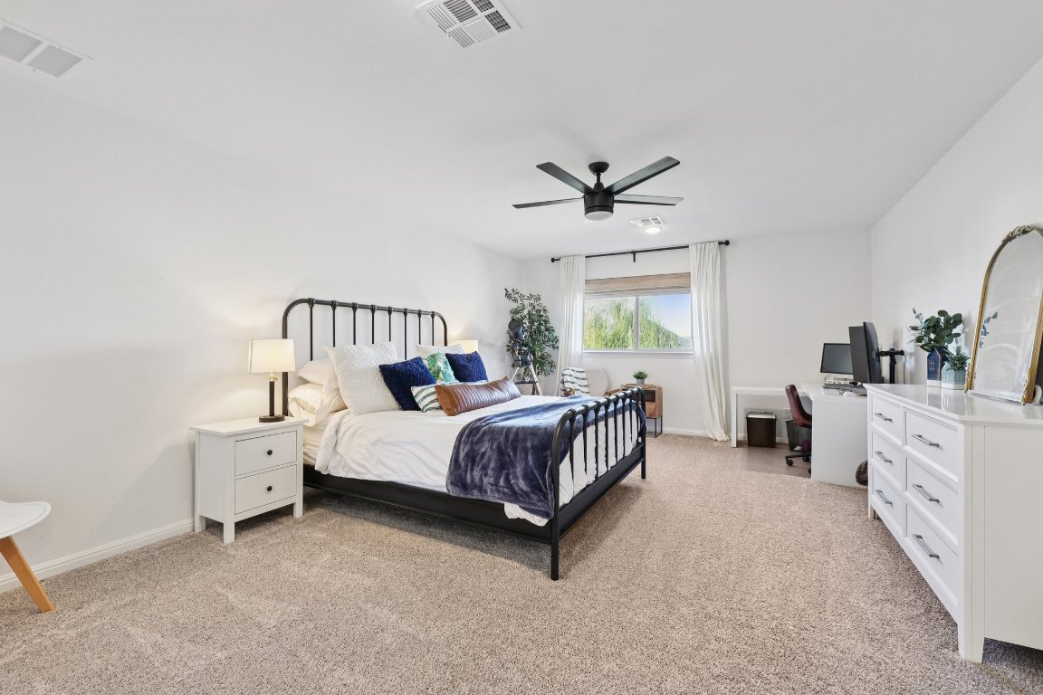 2913 Fallcrest Bend Leander, TX 78641 - Photo 28 of 40 a spacious bedroom with a bed a chandelier and a couch