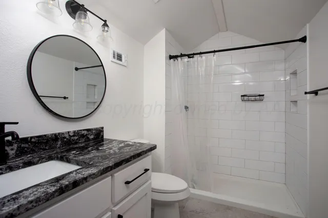 a bathroom with a granite countertop sink mirror toilet and a shower