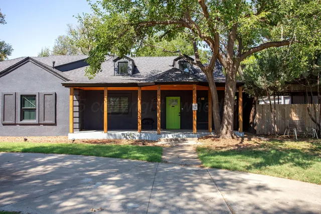 a front view of a house with garden and trees