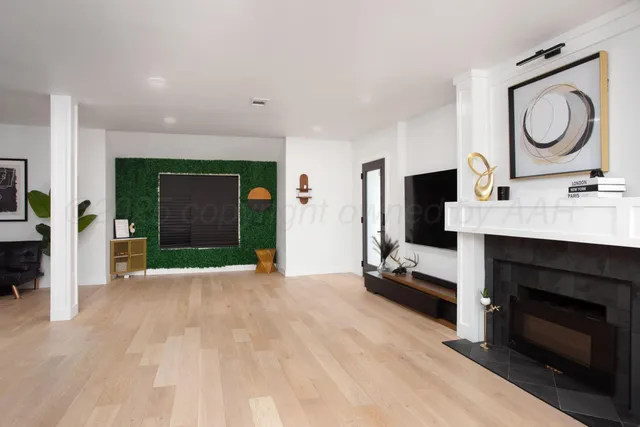 a view of an empty room with kitchen and fireplace