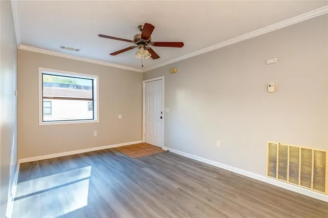 a view of an empty room with wooden floor and a window