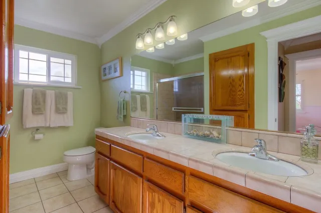 a bathroom with a granite countertop sink a toilet a mirror and a shower