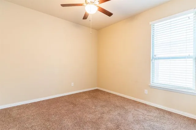 an empty room with a window and a fan